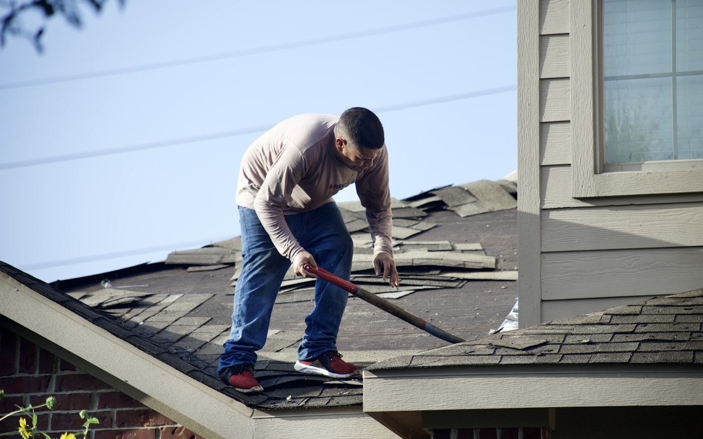 A roofer stripping shingles from a roof
